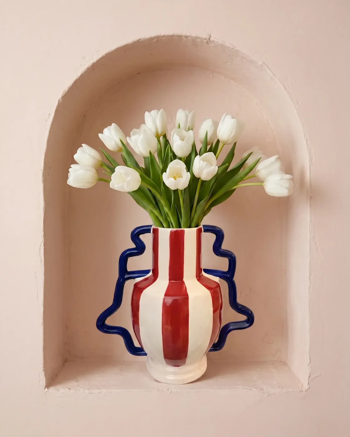 Vaso listrado com tulipas brancas em um nicho rosado